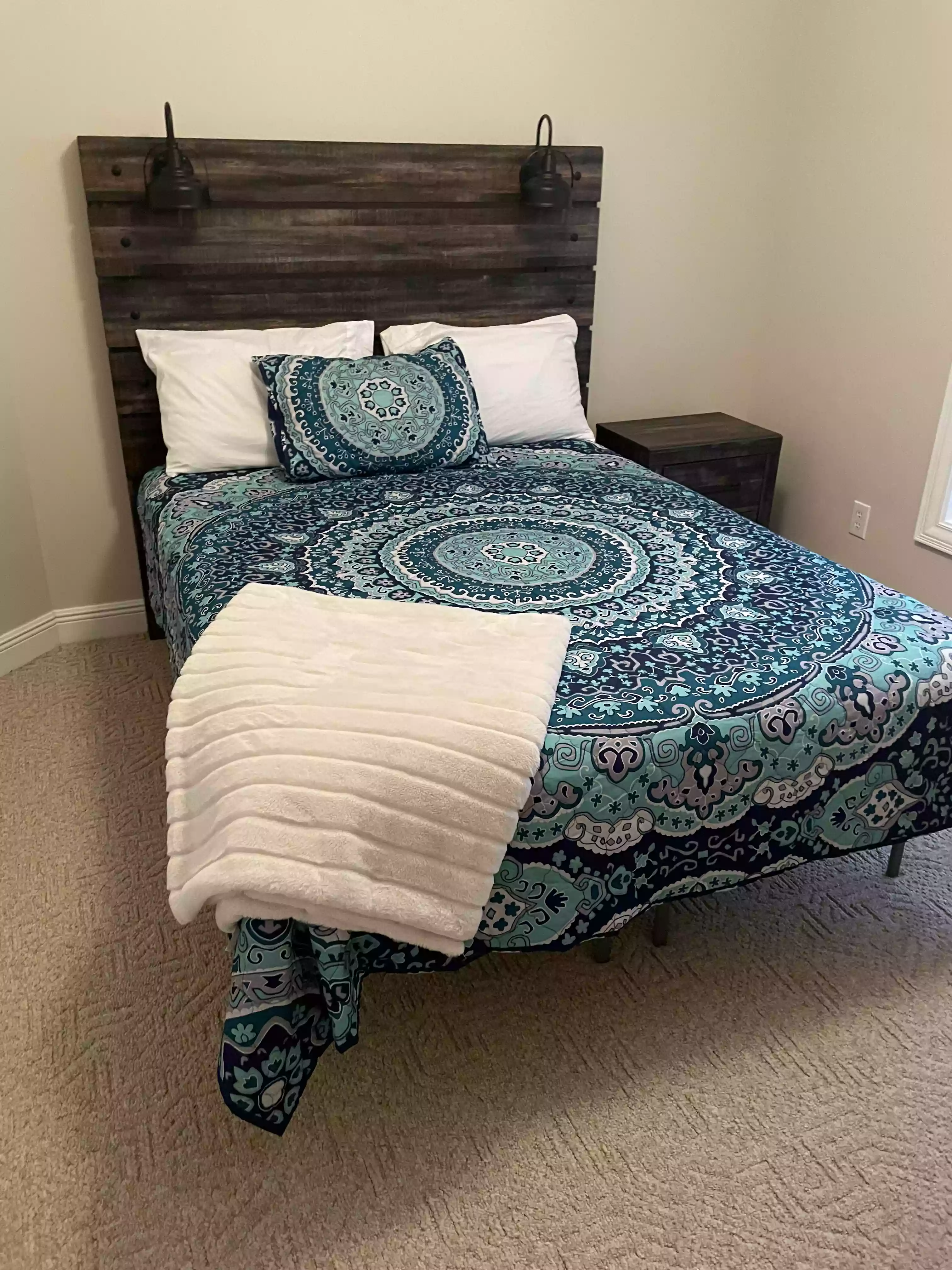 a clean and cozy bedroom area featuring a bed with a blue quilt and an extra fuzzy blanket